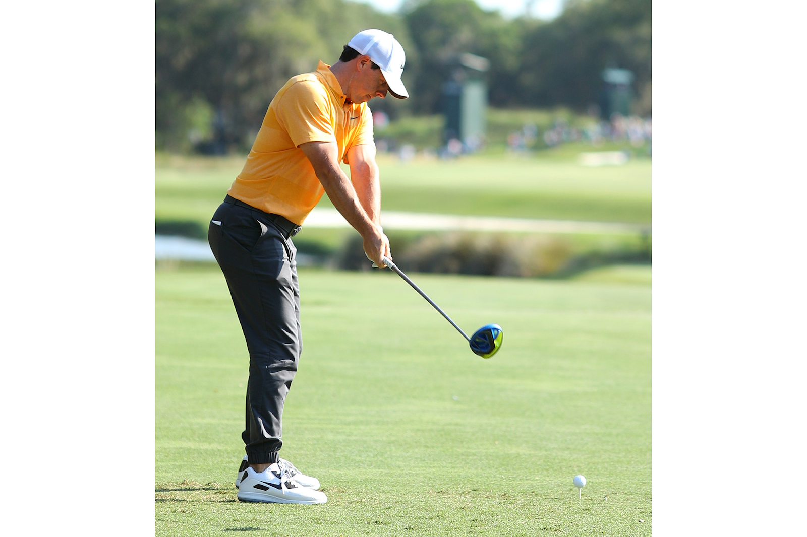 A middle aged man on the golf course hitting a driver on a teed up golf ball 