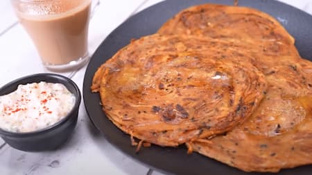 Serving the hot and crispy Onion Laccha Paratha with a side of raita and pickles, ready to enjoy.
