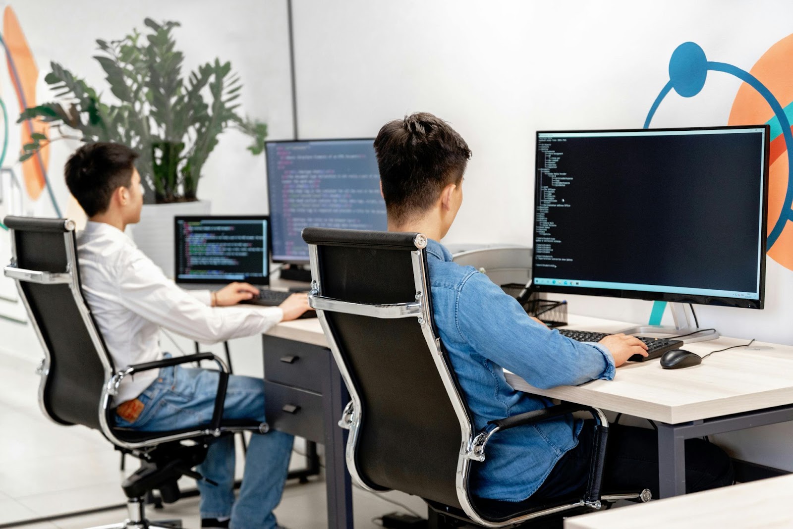 Two professionals working at their desks in an office focused on their computer screens.