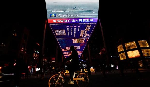 A person riding a bicycle under a sign

Description automatically generated