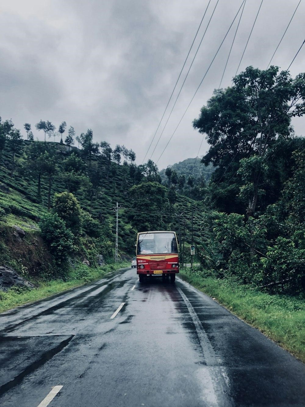 a red bus driving down a wet road