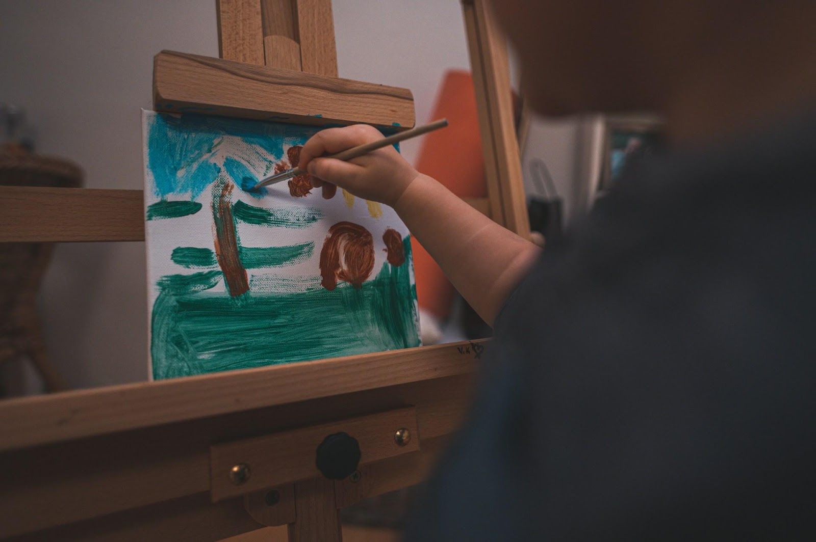 A kid painting on a mini canvas with a paintbrush