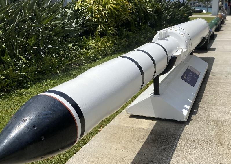 A white and black rocket on a stand

Description automatically generated