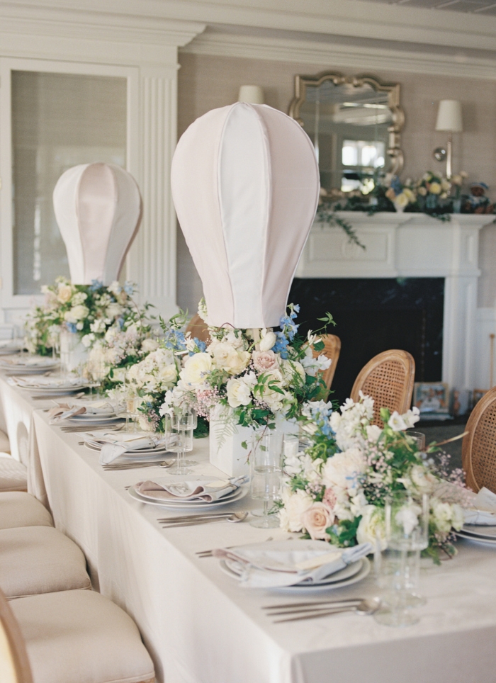 white table set for baby shower with flowers and white hot air balloons