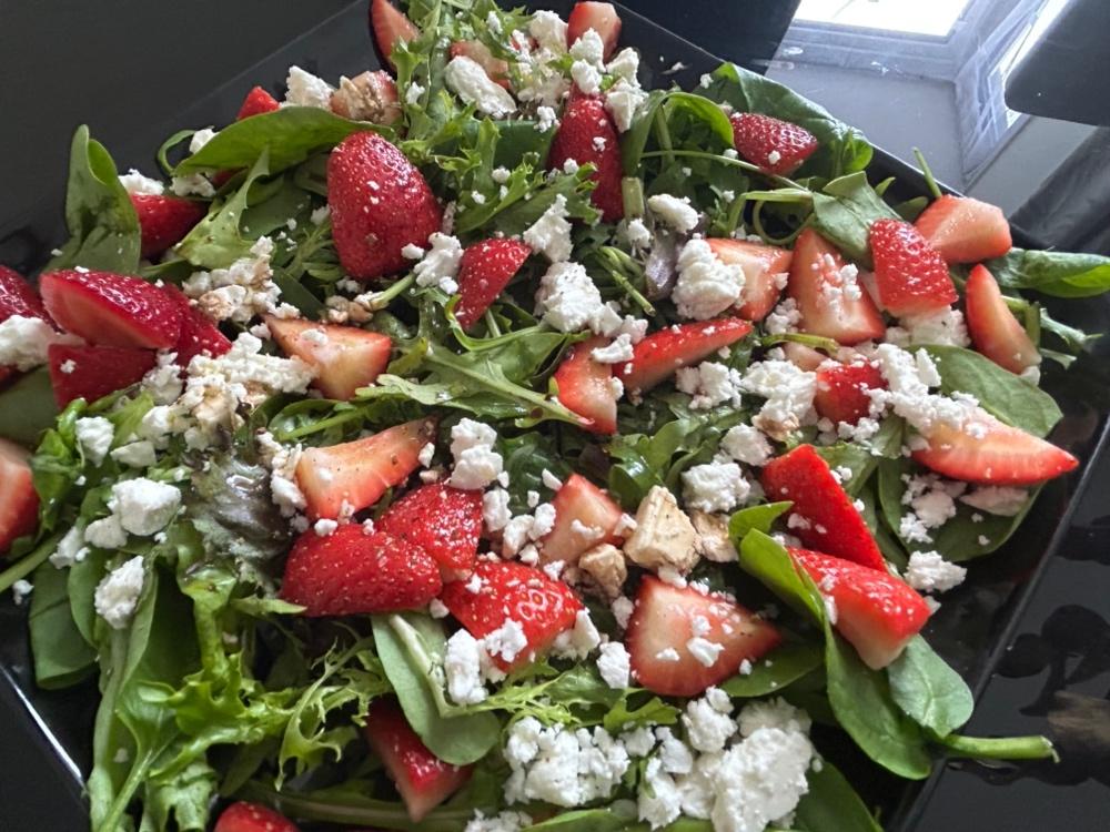 A salad with strawberries and cheese

Description automatically generated