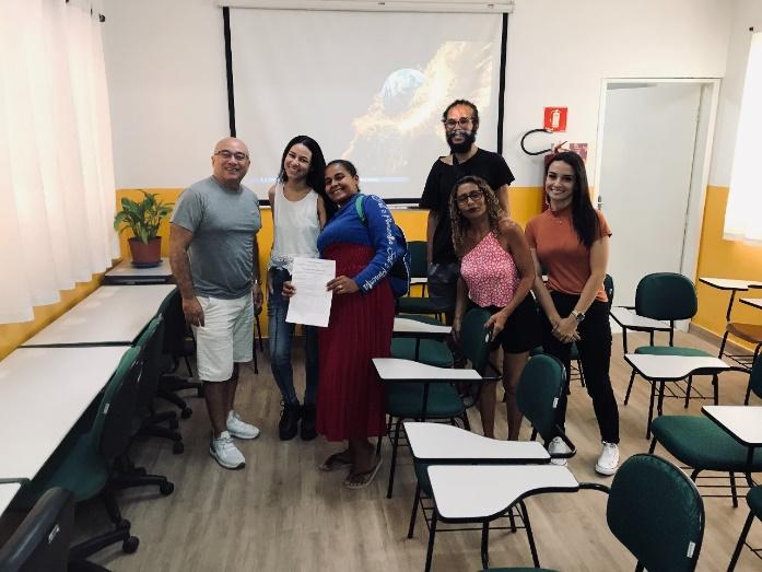 Grupo de pessoas posando para foto em frente a computador

Descrição gerada automaticamente