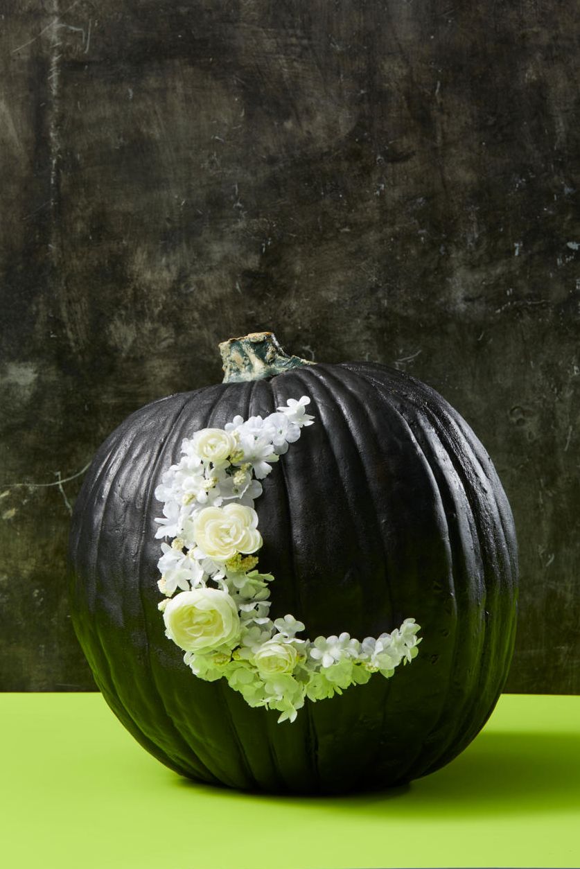 pumpkin carving ideas, black pumpkin with moon shaped flowers attached to the front