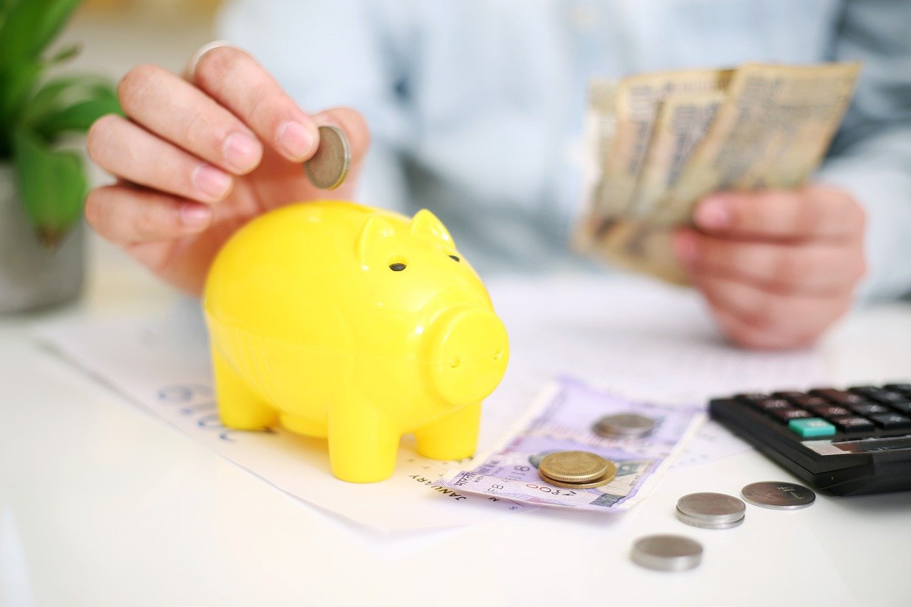 お金を計算して貯金箱に入れている男性