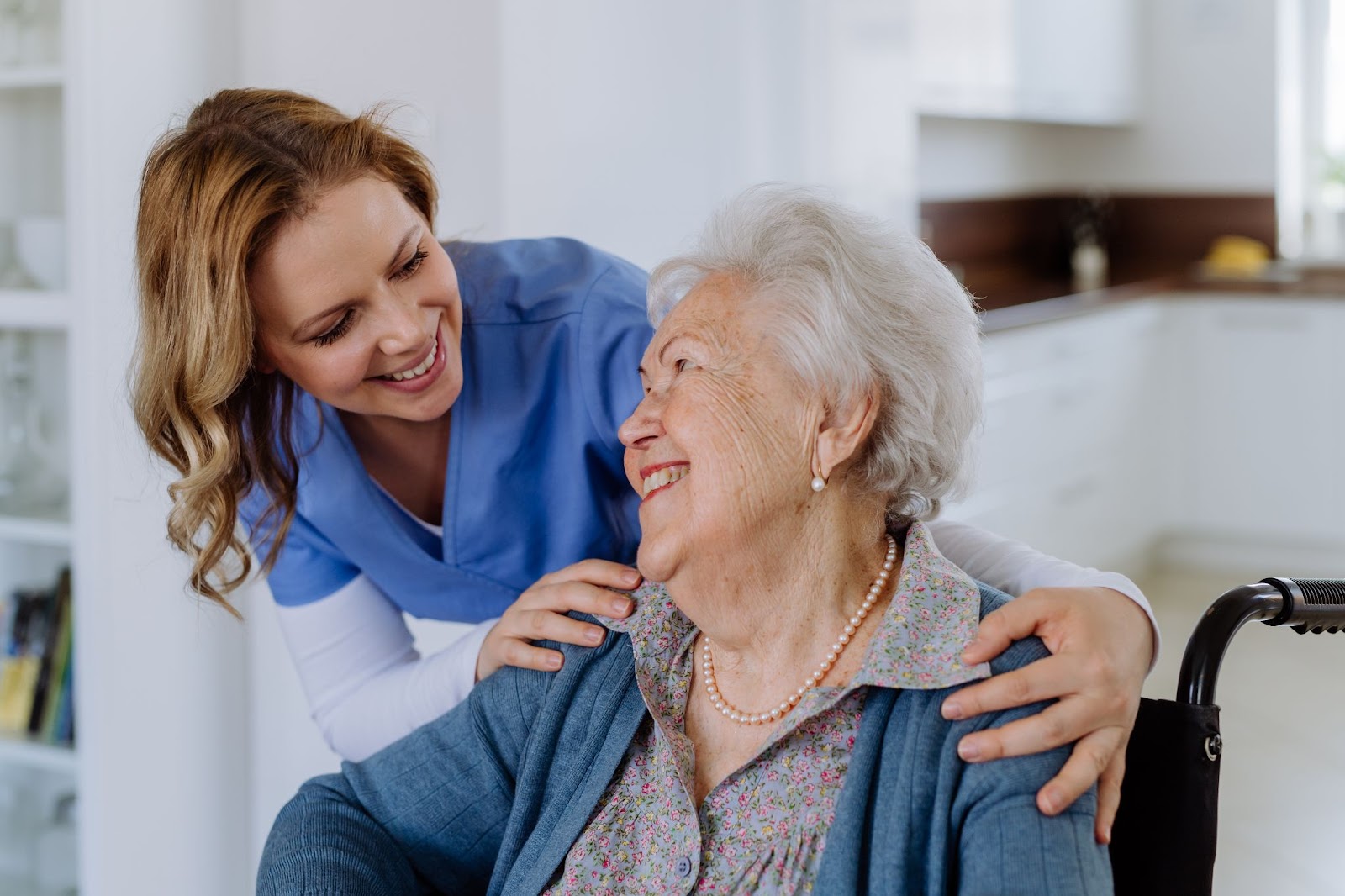A senior woman and her caregiver smiling at each other in respite care.