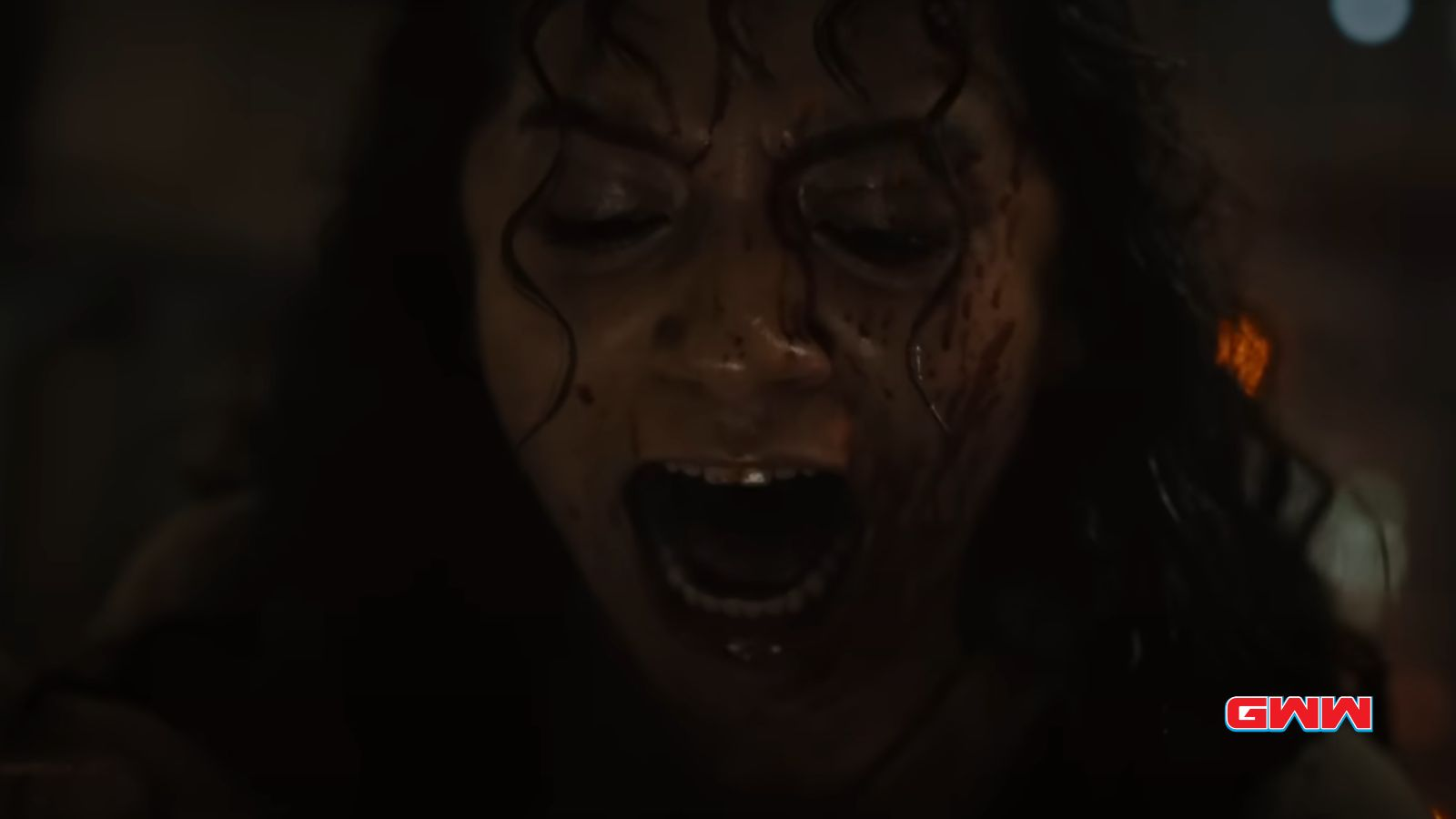 Kay screaming with a blood-covered face in a dark scene.