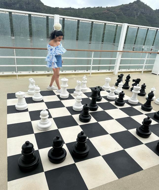 A person standing next to a chessboard

Description automatically generated