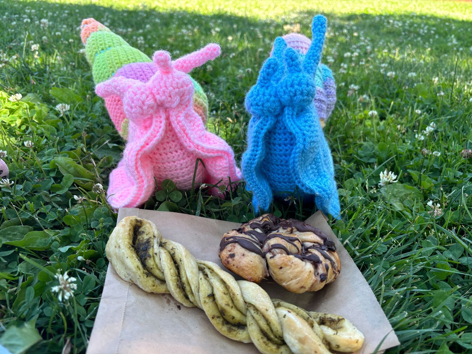 Two snails in the grass with two pastries laid out in front of them