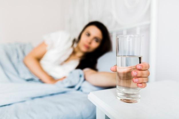 Mulher na cama segurando o copo de água
