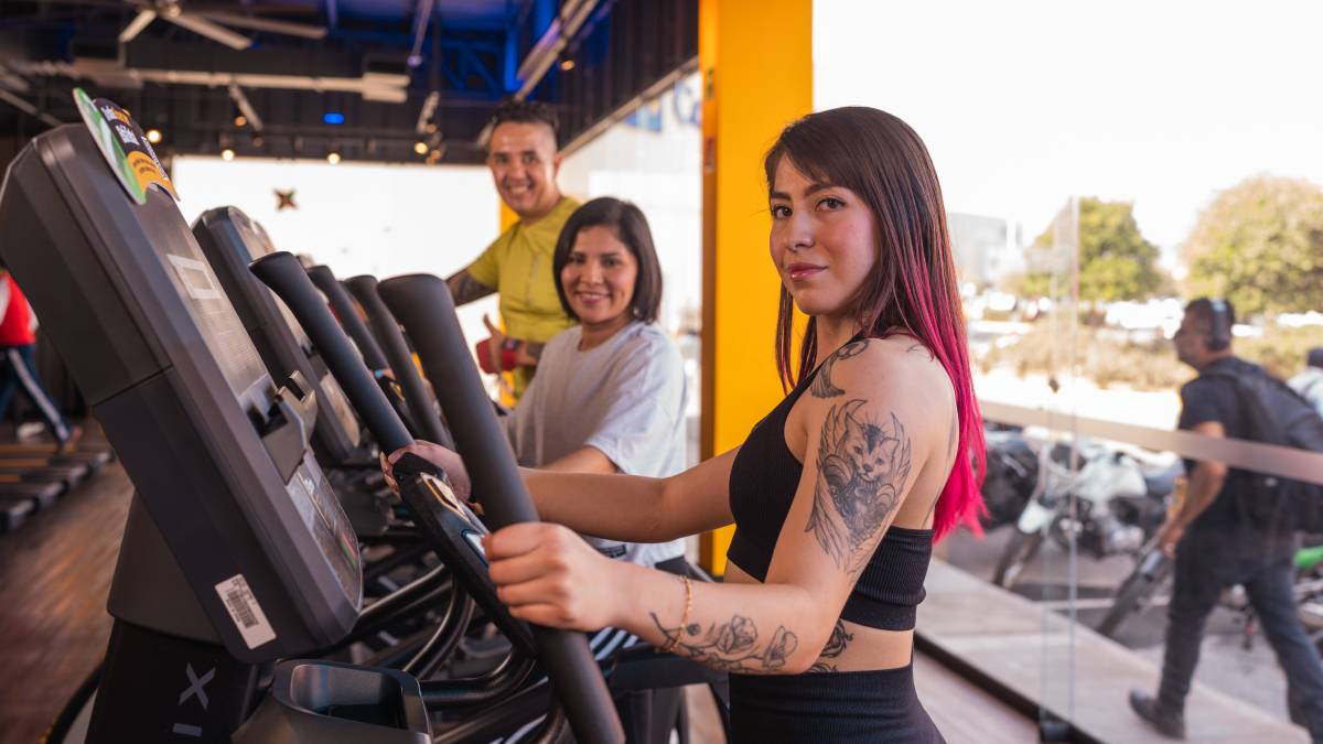 dos mujeres y un hombre realizando ejercicio en las elipticas de un gimnasio Smart Fit