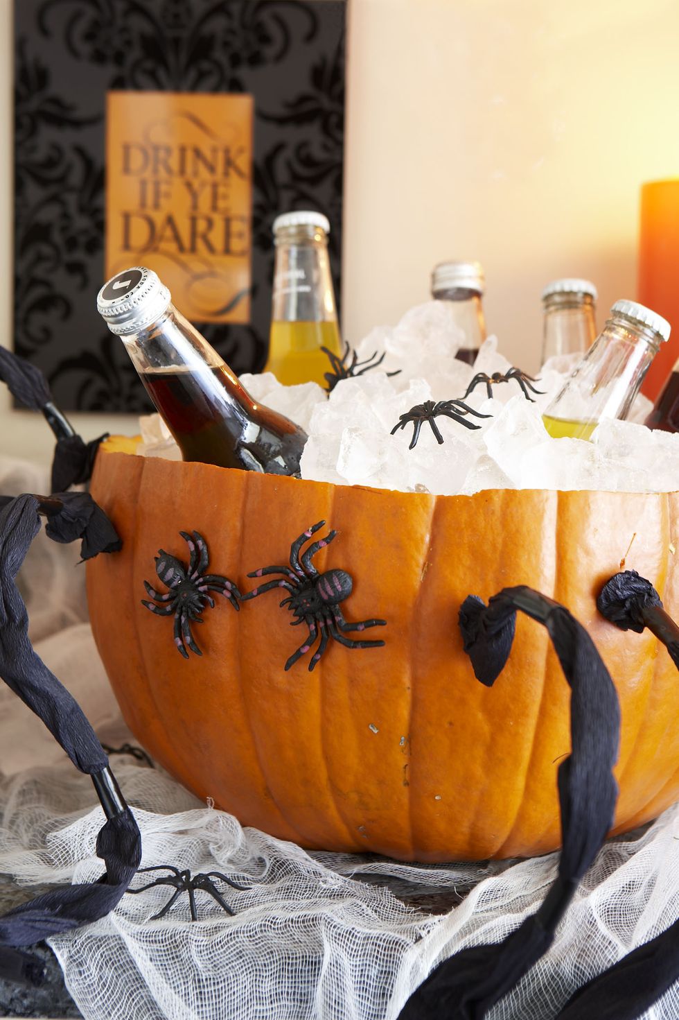 pumpkin carving ideas, cut open pumpkin with drinks inside and spider decorations