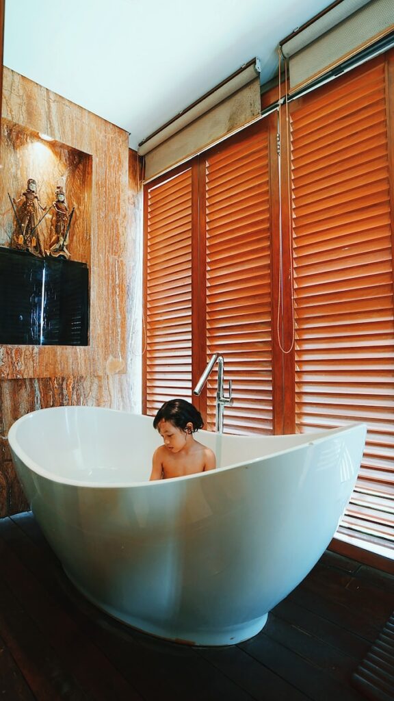 woman in white bathtub holding black smartphone