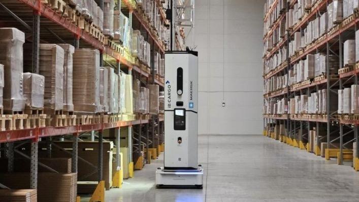 Photo showing a Dexory robot with the tower extended scanning a rack in a warehouse