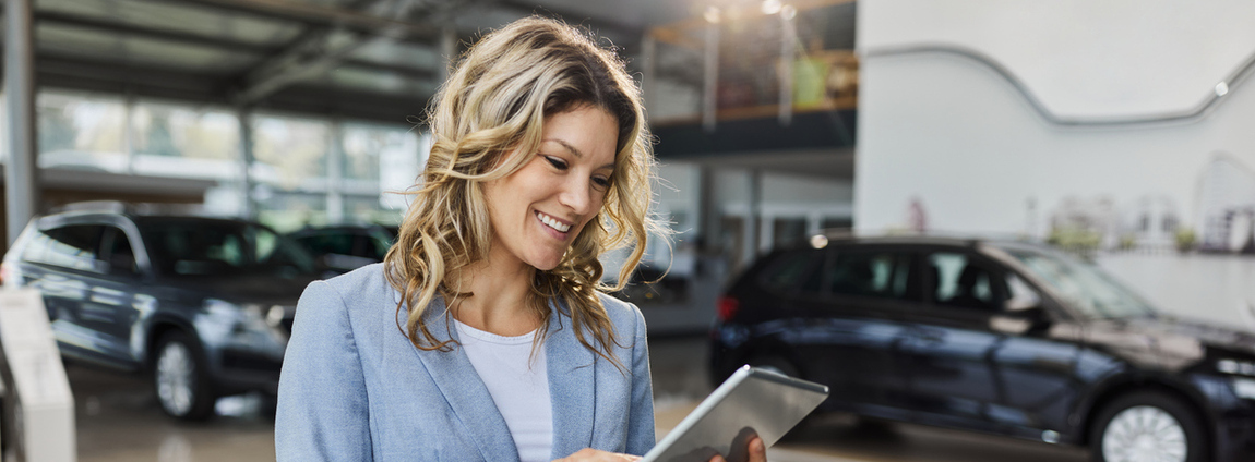 mulher olhando tablet perto da frota de carros