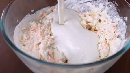 Mixing bowl with grated vegetables, rice flour, and mashed potatoes being combined into a batter.