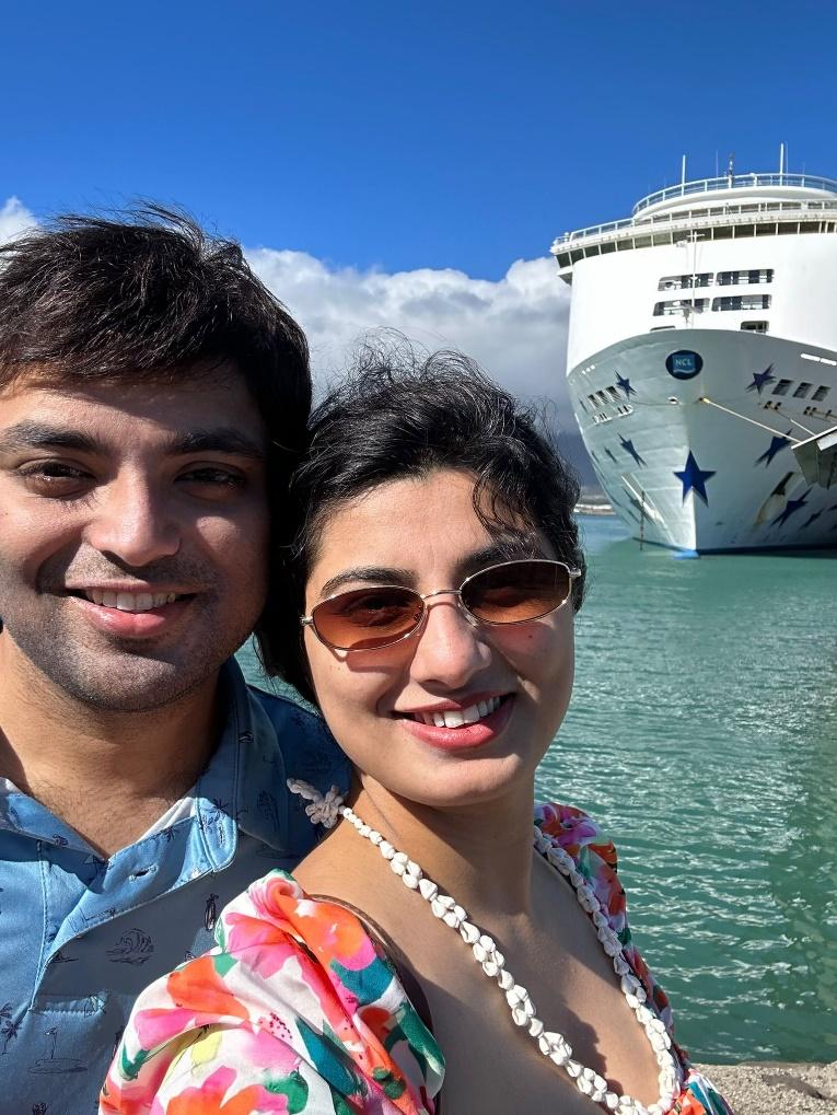 A person and person taking a selfie in front of a cruise ship

Description automatically generated