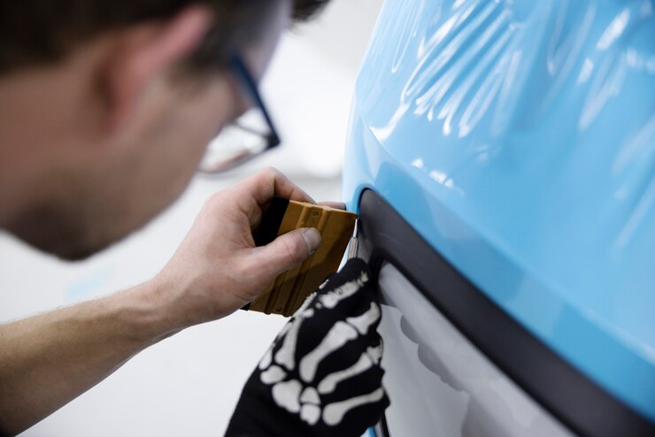 A man is carefully applying car wrap to a car.