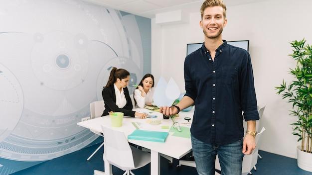 Smiling young businessman with water drop icon standing in office