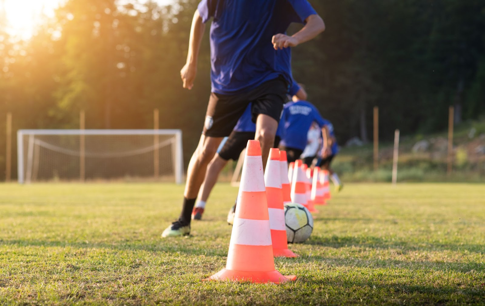 Des joueurs de football s'entraînent en dribblant à travers des plots.
