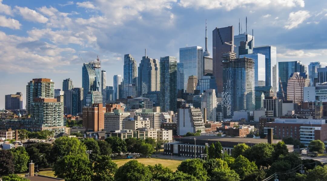 Vue panoramique de la ligne d'horizon d'une ville avec de grands gratte-ciels et un parc verdoyant au premier plan.