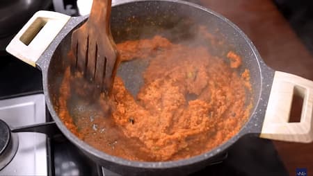 Cooking onion paste with spices in a pan until golden brown.