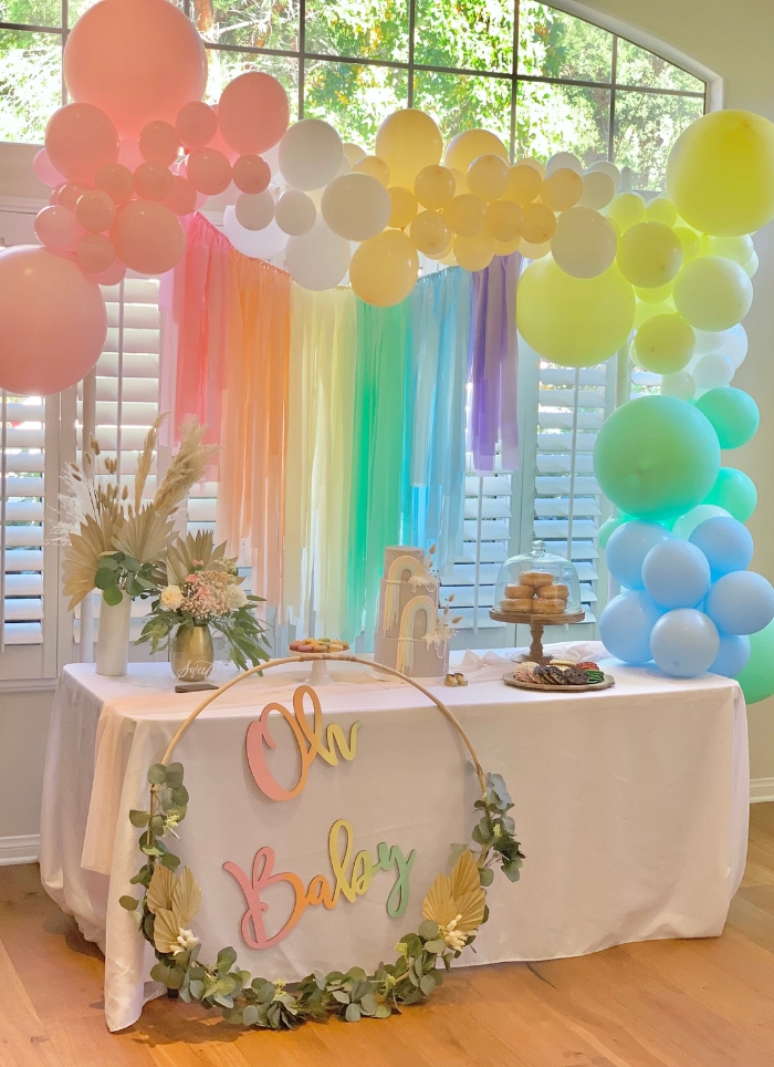 rainbow balloon arch over oh baby sign and table