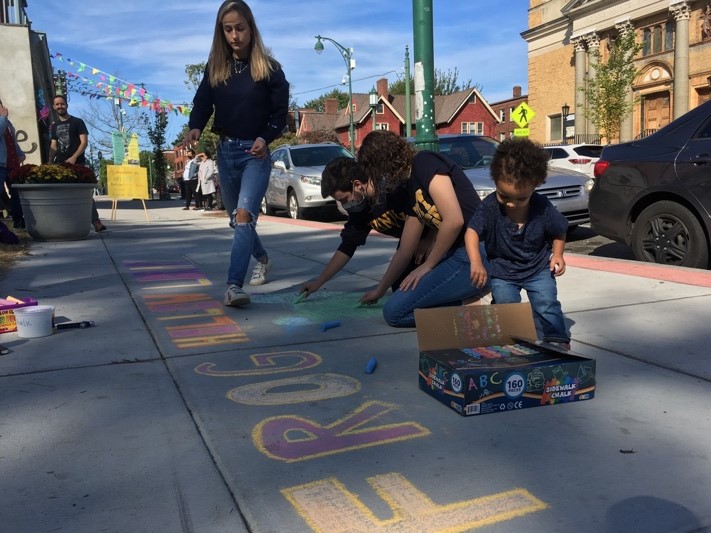 A group of people drawing on the sidewalk

Description automatically generated