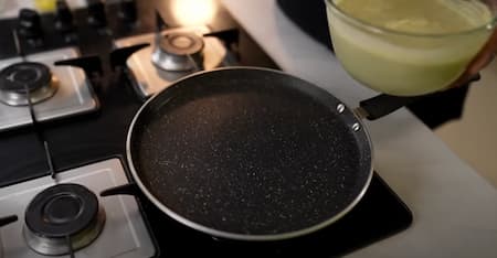 Heating a non-stick pan and preparing it for making the high protein chilla.