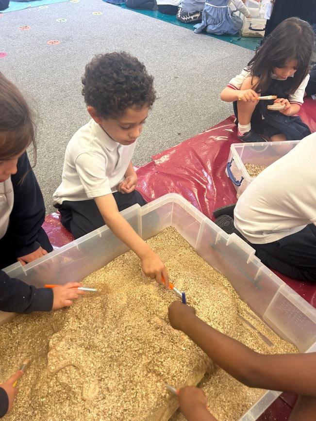 A group of children playing with sand

Description automatically generated