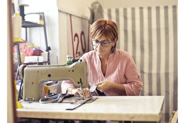 Näherin beim Anfertigen von BündchenStoffen an ihrer Nähmaschine