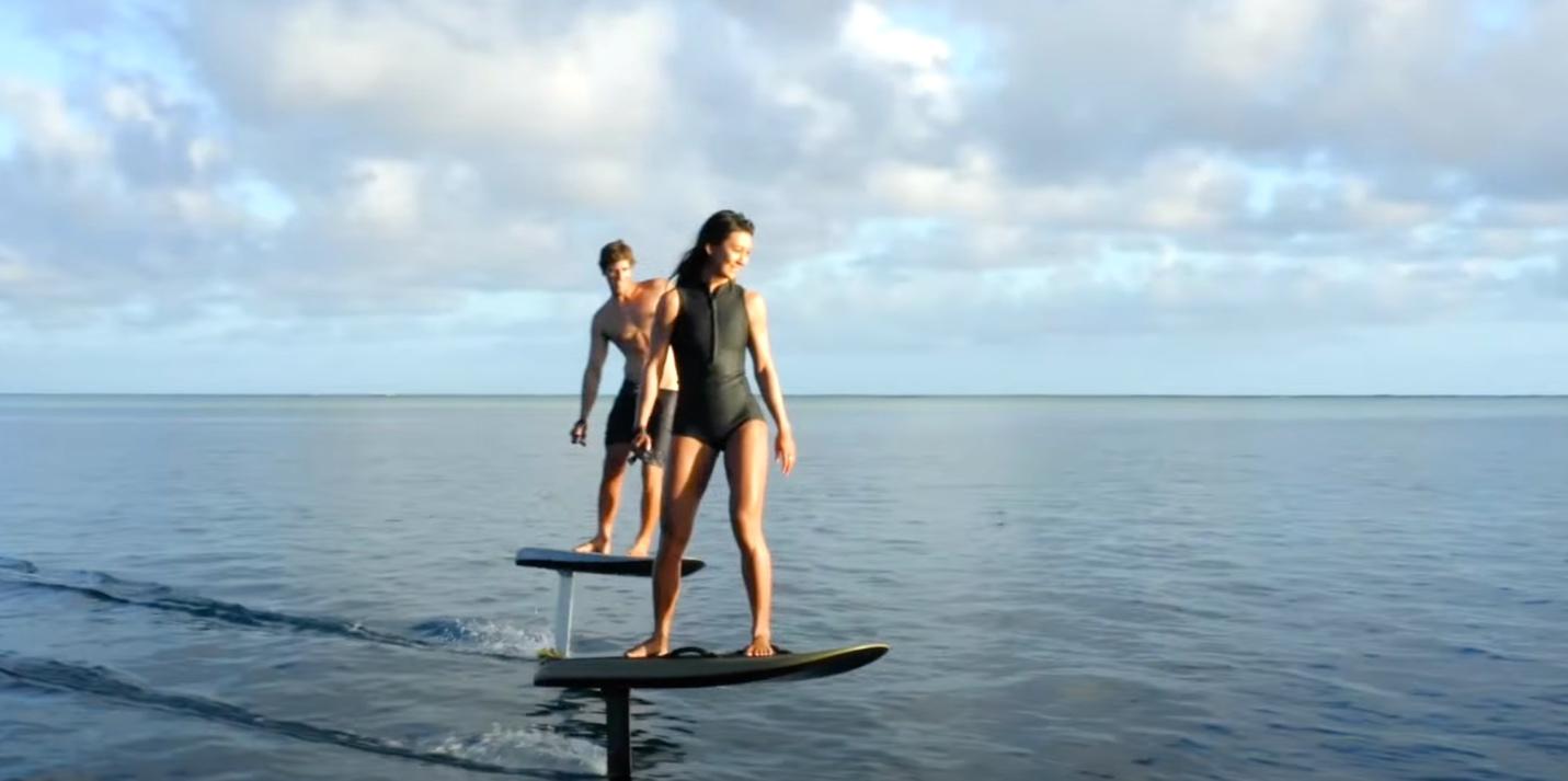 A person and person standing on a surfboard in the water

Description automatically generated