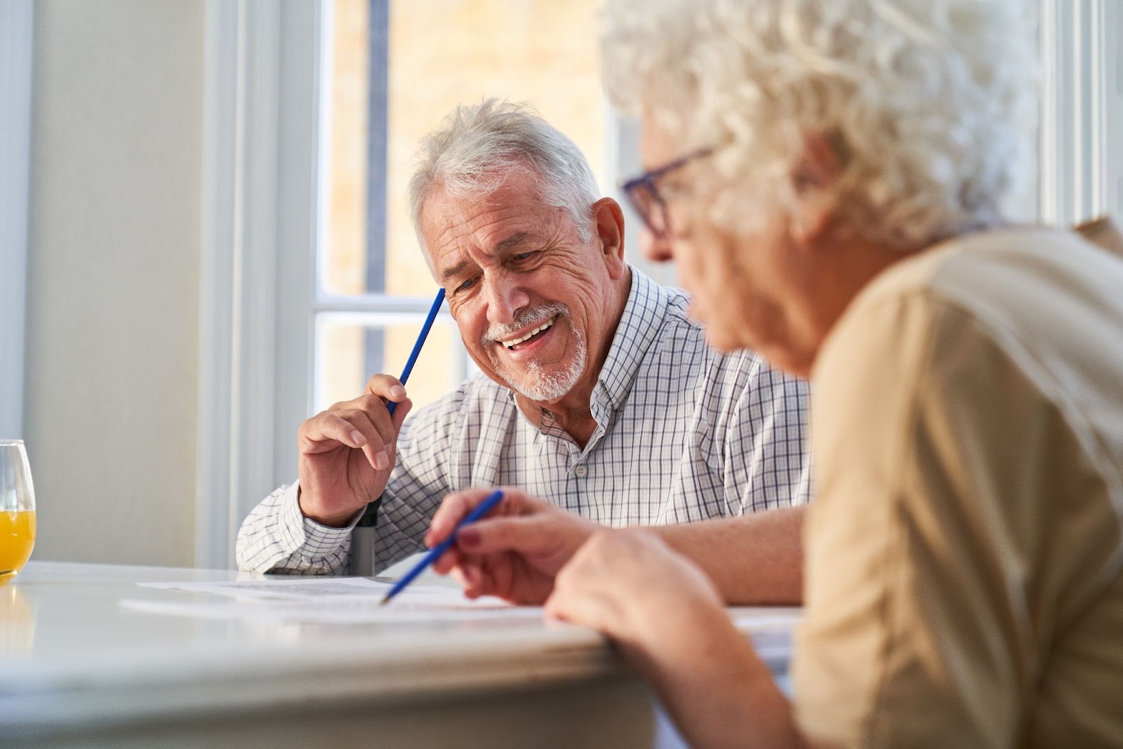 Two seniors in memory care sitting at a table together enjoying a puzzle.