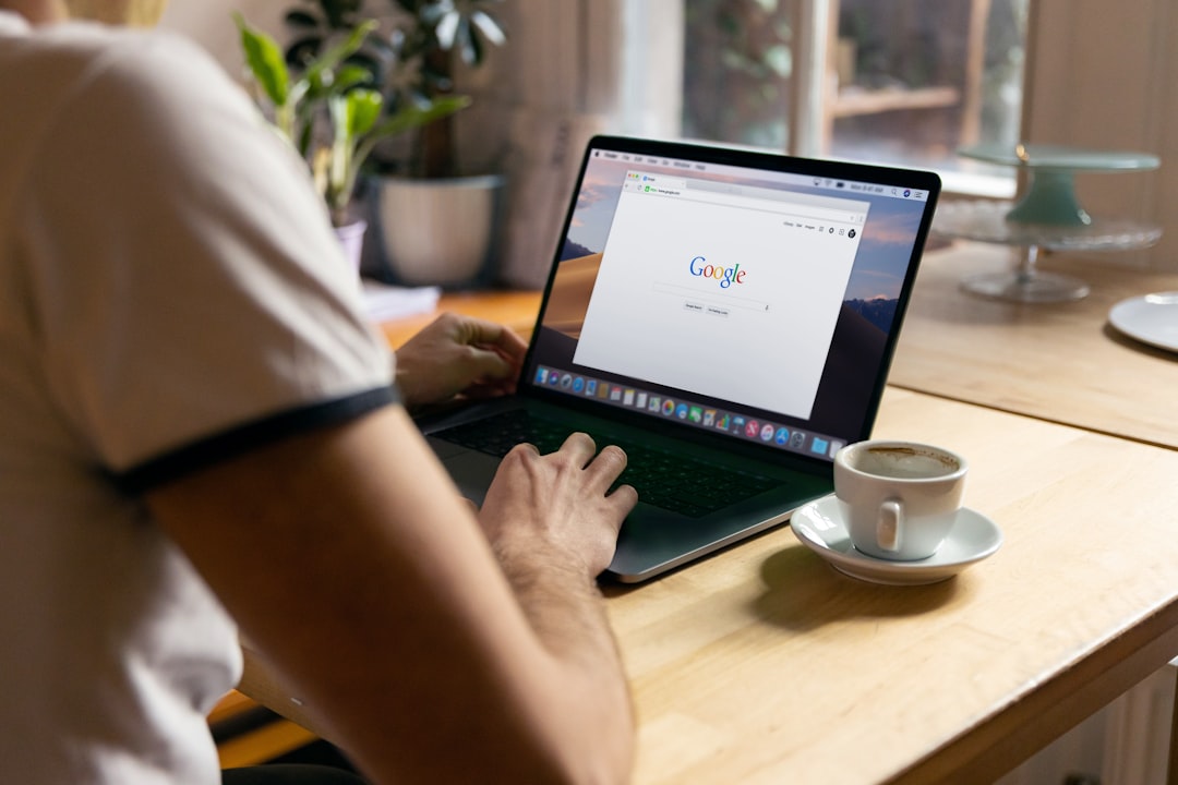 A person typing on a laptop while performing a Google search.