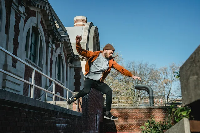 Energetic man jumping from wall in town