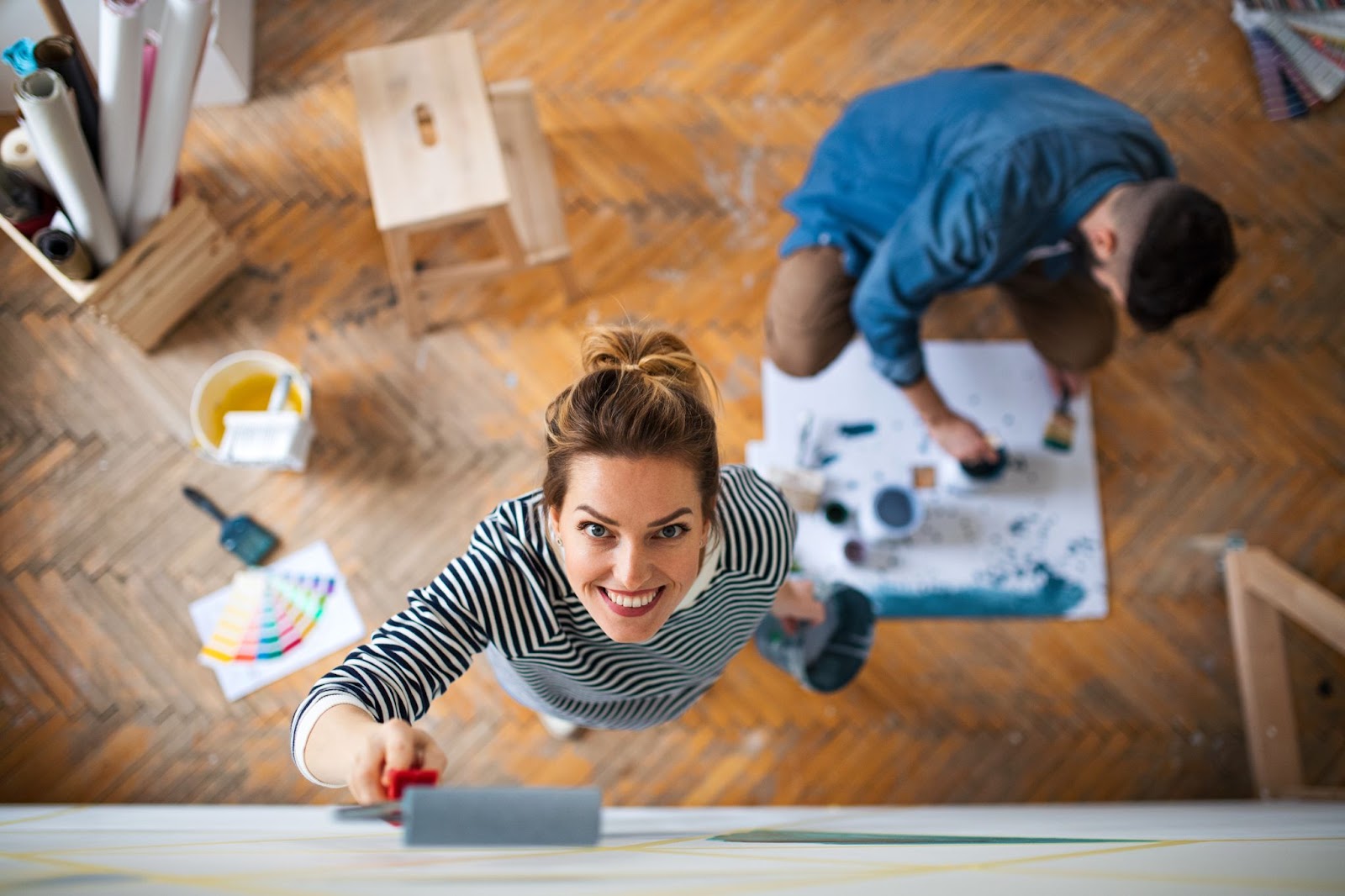 Woman and a man painting and remodeling a home with a wood floor. 