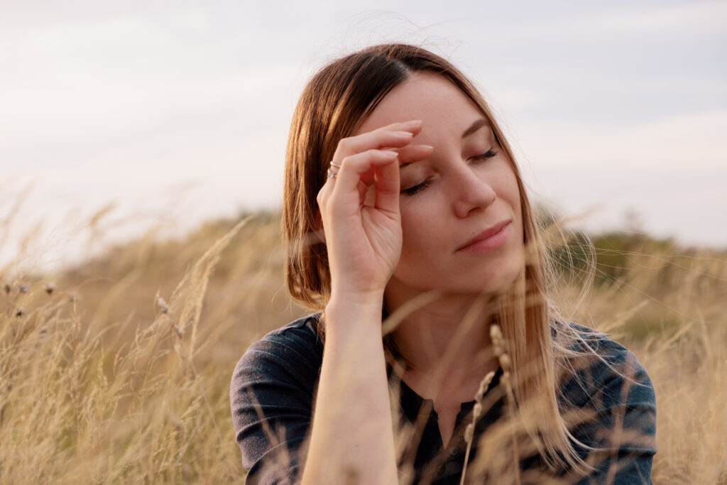 Young woman sat outside in a nature in a wheat field, sat being patient about letting go of her body control