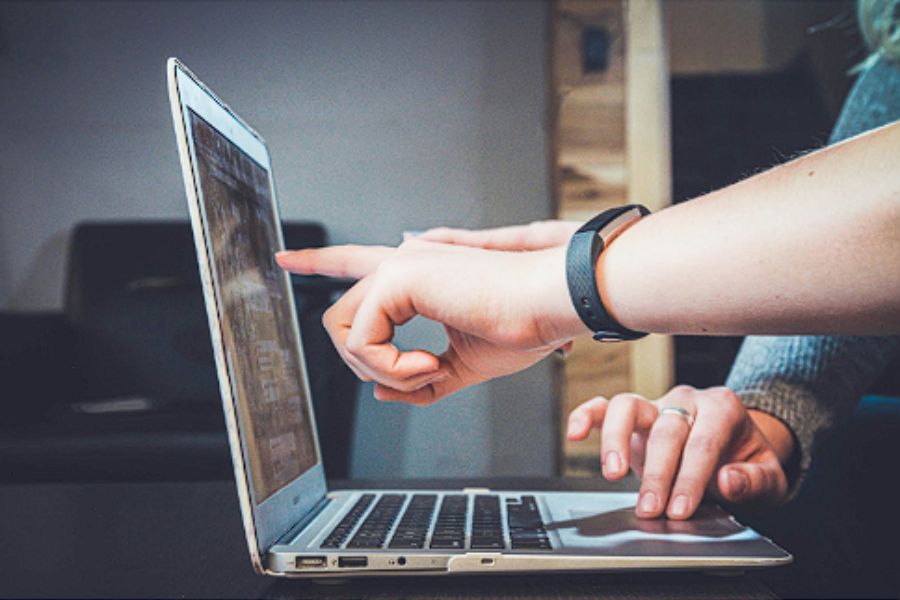 Two people collaborating on a laptop, pointing at the screen.