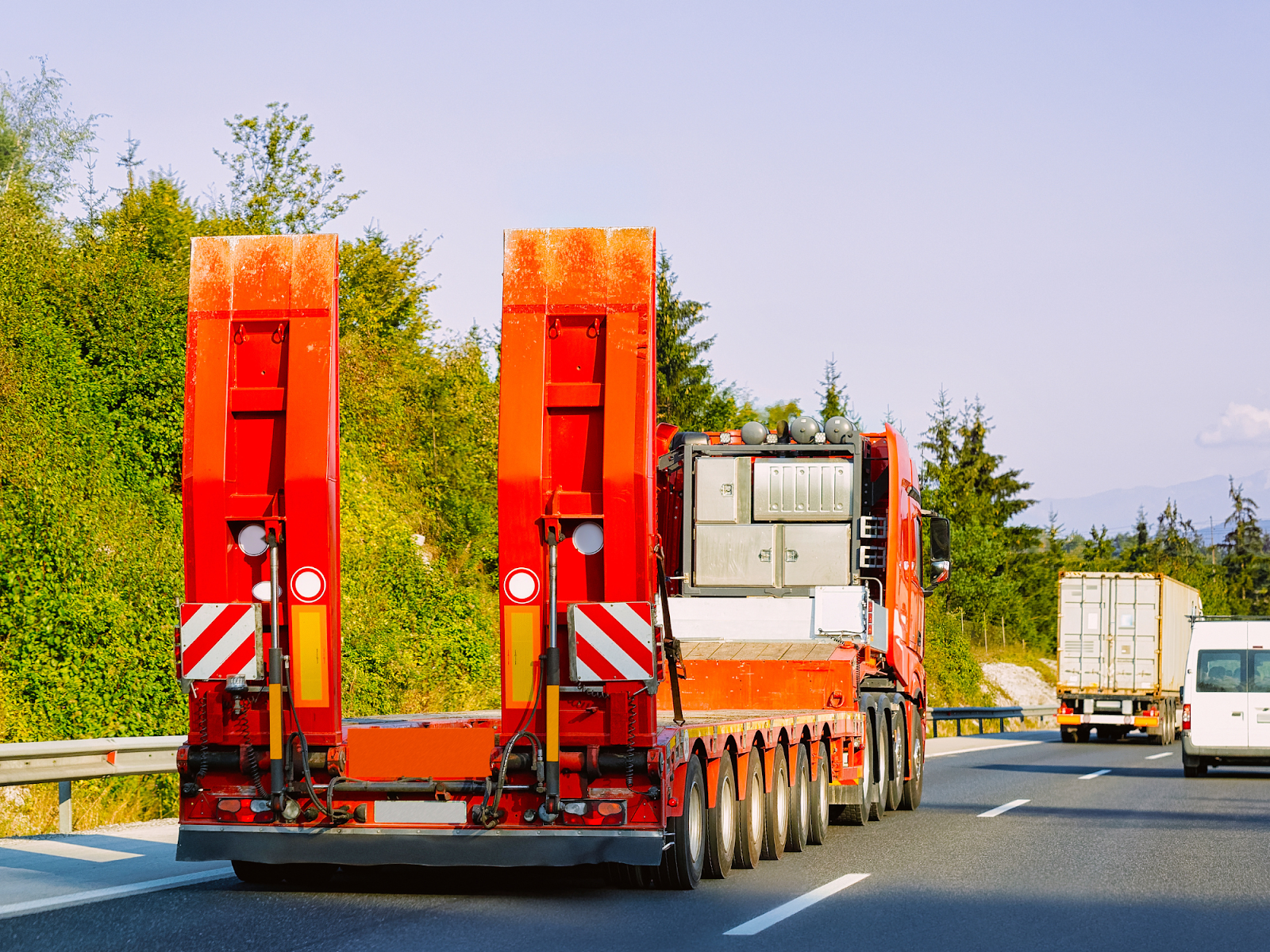 lowboy truck driving on an indiana highway road with other tractor trailers