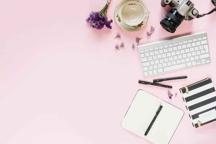 Digital camera; keyboard; felt-tip pens and stationery on pink background