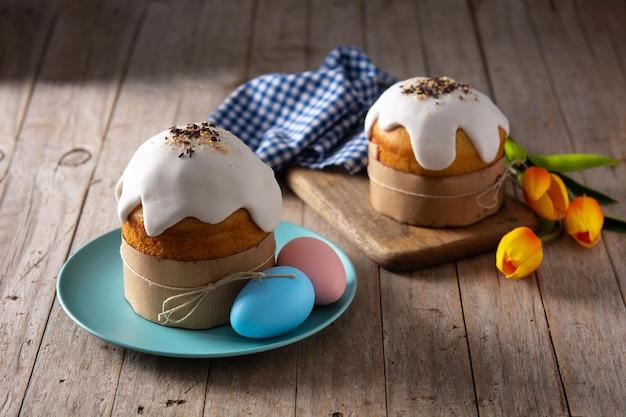 Traditional Easter cake, colorful eggs and tulips on wooden table.