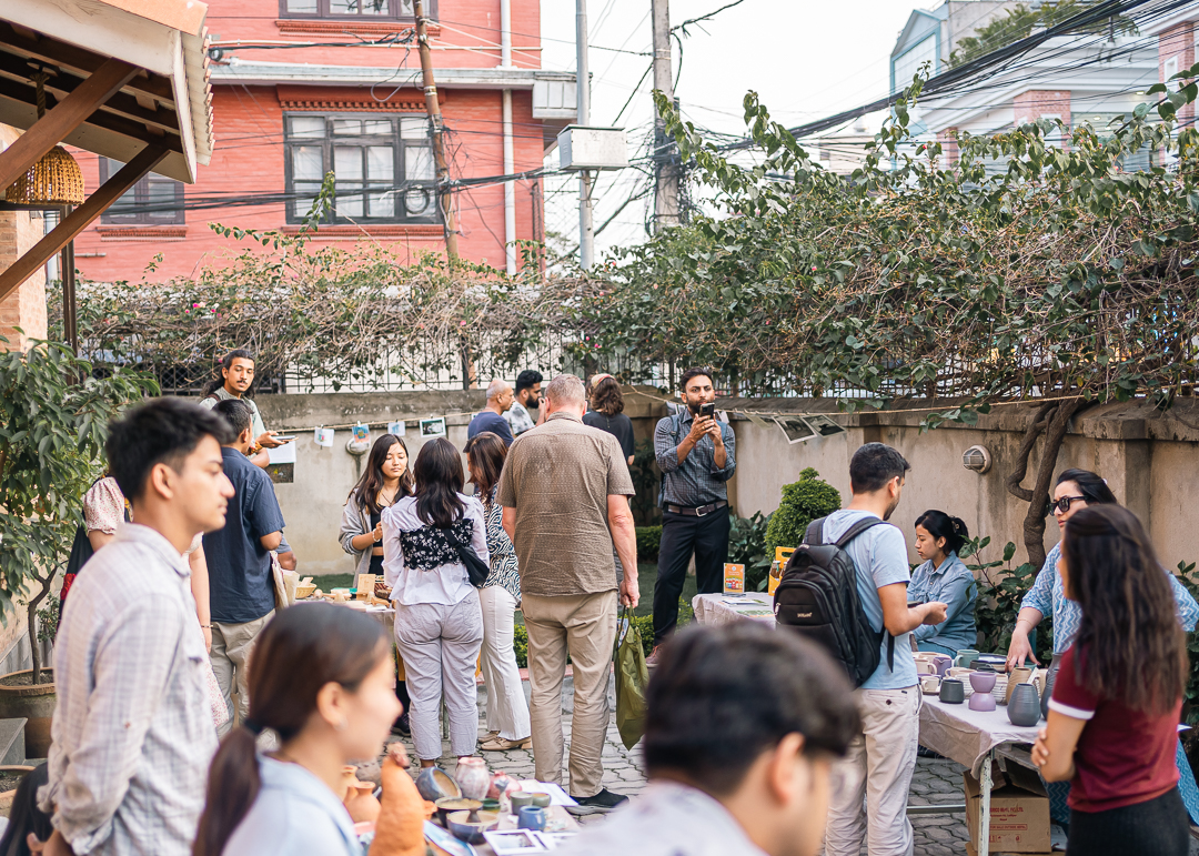 A group of people gathered at an nature’s market, interacting with vendors and exploring eco-friendly products, embodying a local effort within a global sustainability movement.