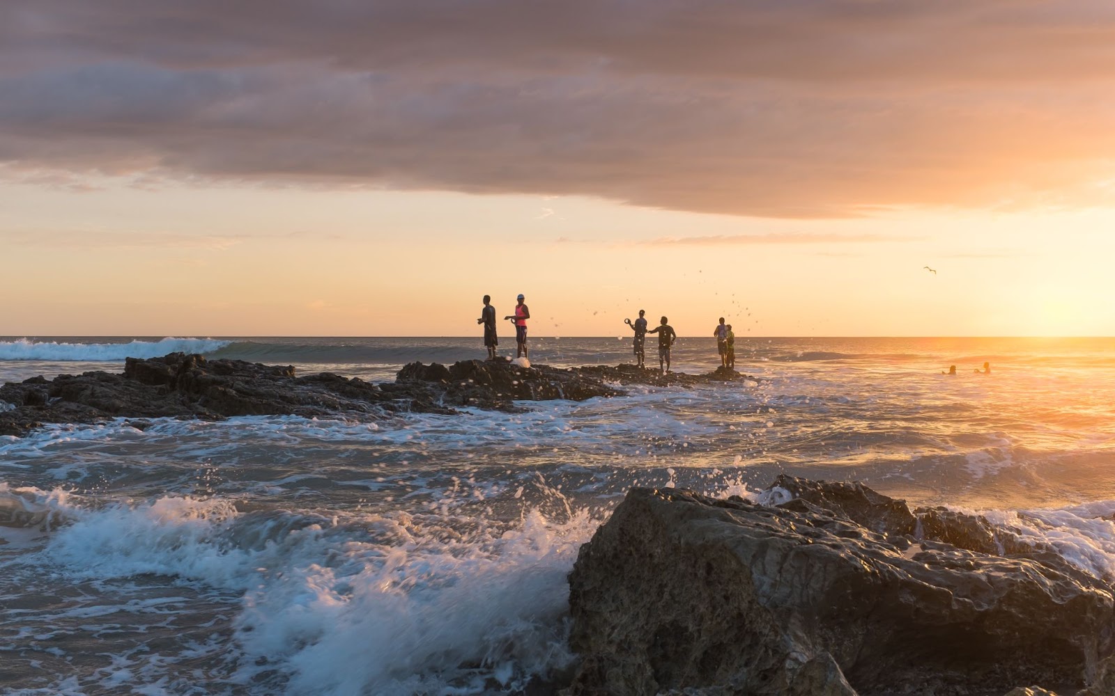 people standing on rocks and adoring beautiful sunset