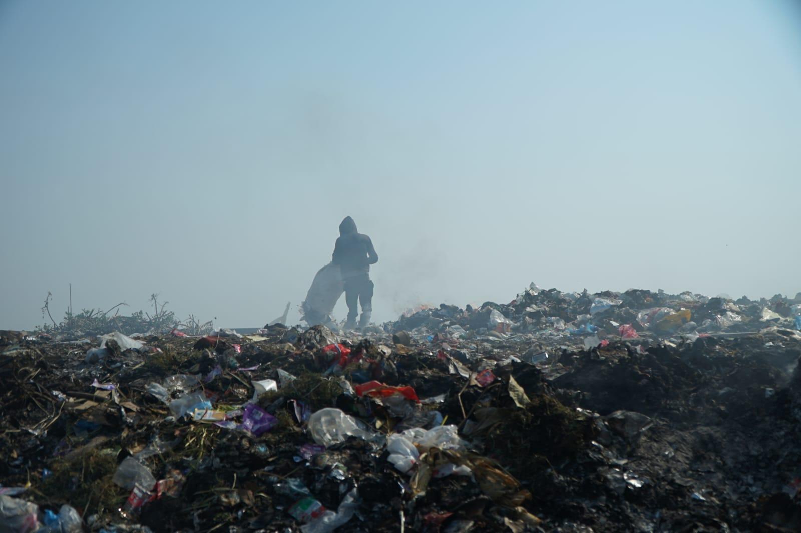 A person standing in a pile of garbage

Description automatically generated