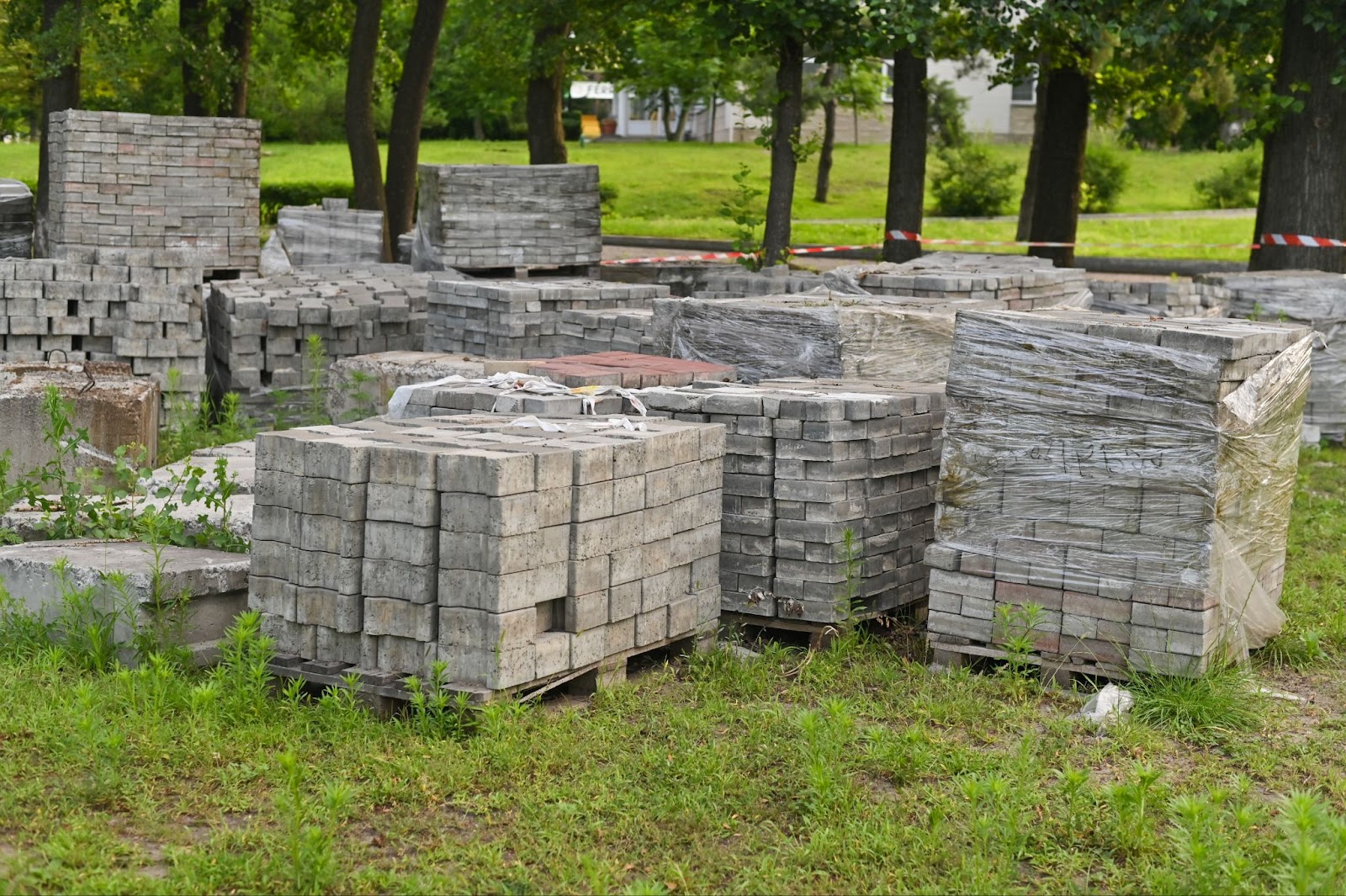 Piles of white bricks stacked in an outdoor warehouse, with trees and plants in the background.