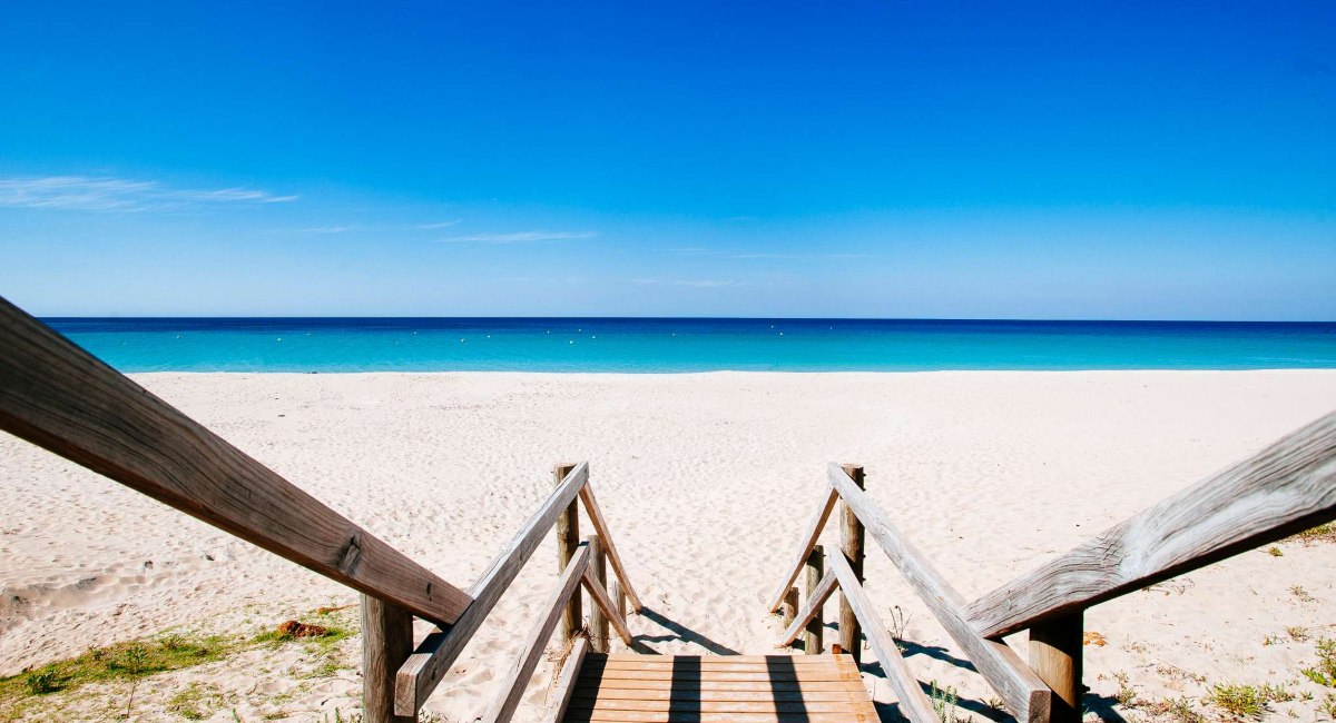 Scenic view from the wooden stairway leading to the pristine white sands and crystal-clear waters of one of Dunsborough beaches, perfect for a relaxing day under the bright blue sky