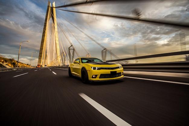 Yellow sport car with black autotuning on the bridge.